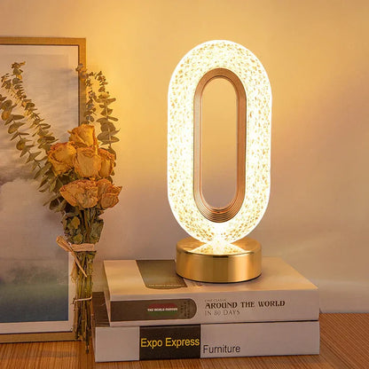 Abajur moderno oval iluminado sobre livros, ao lado de bouquet seco de rosas e quadro com decoração minimalista