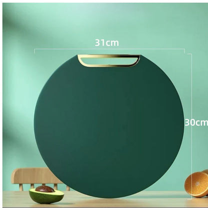 Tábua redonda de corte verde escura com alça dourada, 31x30 cm, sobre mesa com abacate e laranja