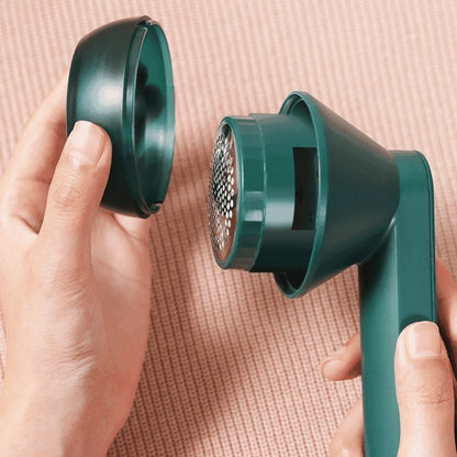 Máquina removedora de fiapos verde sendo desmontada contra fundo rosa texturizado