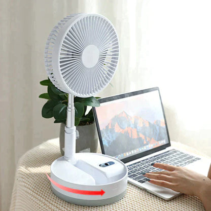 Ventilador portátil branco em mesa com notebook aberto e planta ao fundo, ambiente iluminado