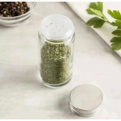 Tempero seco verde em pote de vidro com tampa branca, especiarias na mesa de cozinha