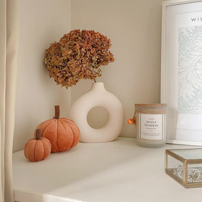 Decoração outonal com vasos de cerâmica, flores secas, abóboras decorativas de veludo e vela maple pumpkin