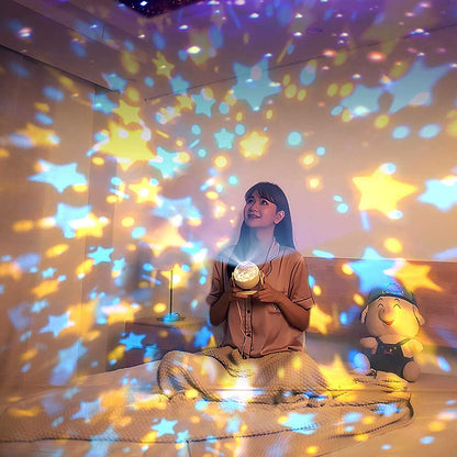 Mulher sentada na cama segurando projetor de estrelas coloridas, quarto aconchegante iluminado