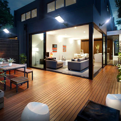 Casa moderna com deck de madeira iluminado por refletores solares de LED e área externa mobiliada