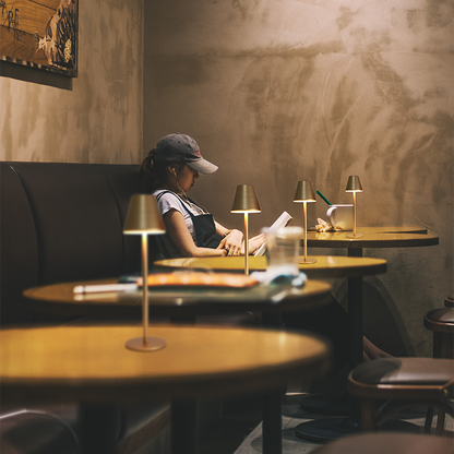 Pessoa lendo em café com iluminação de lâmpadas de mesa em ambiente aconchegante