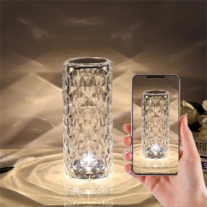 Vaso de vidro cristal com luz LED refletindo padrão geométrico, segurado por mão com smartphone