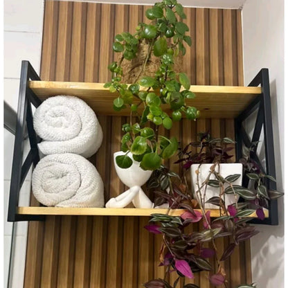 Prateleira de madeira com estrutura preta contendo toalhas enroladas e vasos com plantas decorativas