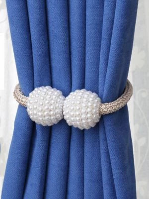 Prendedor de cortina com acabamento em pérolas brancas, segurando cortina azul dobrada