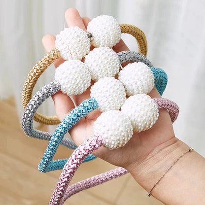 Cabeças de cortina trançadas coloridas com bolas de pérolas brancas nas pontas, exibidas em mão