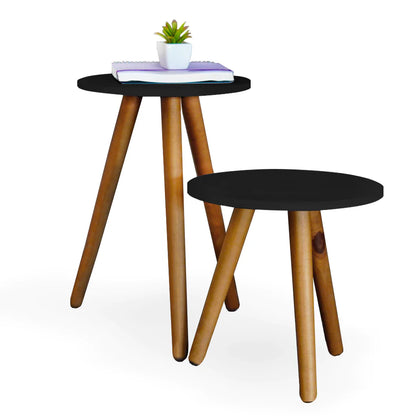 Conjunto de mesas de centro redondas com tampo preto e pernas de madeira clara, mesa menor na frente e maior com livro e planta