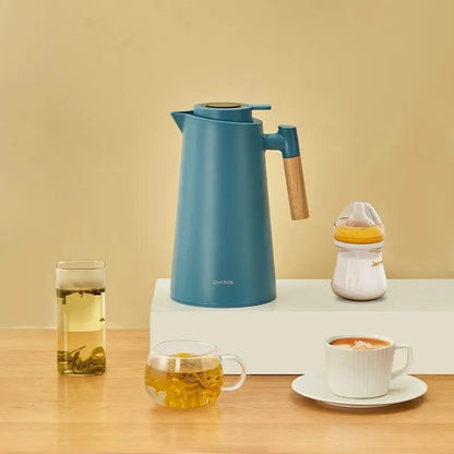 Garrafa térmica azul com termômetro digital e alça de madeira, chá em copos transparentes e xícara de café em superfície de madeira