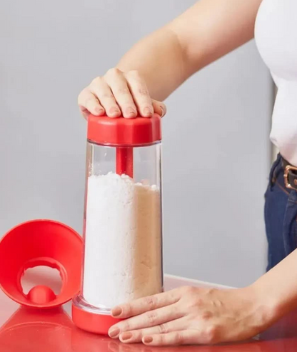 Moedor manual vermelho para farinha com tampa removida, mãos ajustando aparelho na cozinha