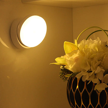 Luz noturna LED redonda com sensor PIR na parede, decorada com arranjo floral amarelo e branco
