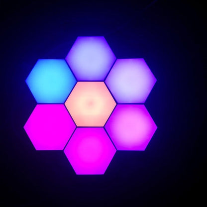 Luminária de parede hexagonal com sete painéis coloridos em tons de azul, rosa e lilás iluminados
