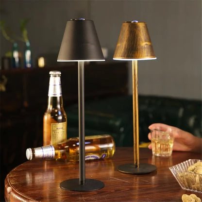 Duas luminárias de mesa em ferro estilo nordico, com garrafas de cerveja e copo de bebida sobre mesa de madeira