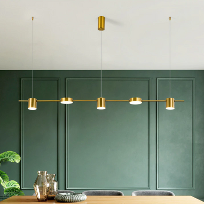 Luminária moderna dourada suspensa sobre mesa de madeira em sala com parede verde escura e decoração minimalista