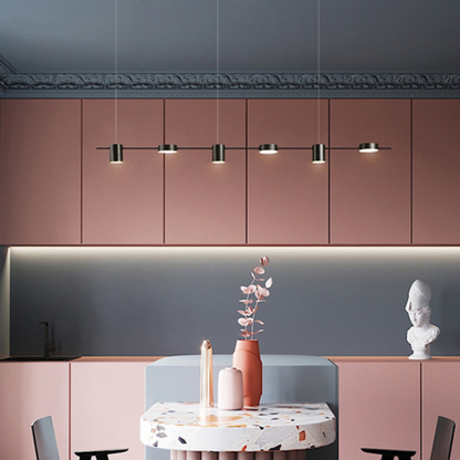 Cozinha moderna com armários rosa, luminárias pendentes e mesa de pedra com vasos decorativos