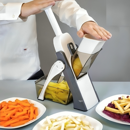 Pessoa usando mandoline para cortar batata em tiras, com pratos de legumes variados sobre a mesa