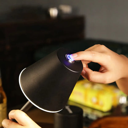 Mão feminina acionando sensor de toque em luminária preta com luz branca