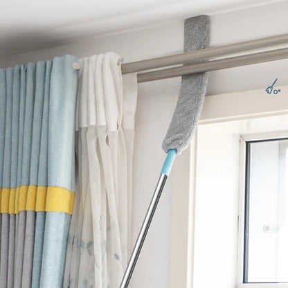Pano de microfibra cinza em cabo telescópico limpando varão de cortina em ambiente residencial