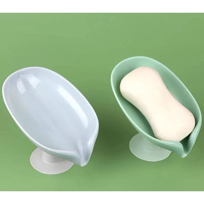 Dois saboneteiros com ventosas, um verde com sabonete branco e um azul claro vazio sobre fundo verde