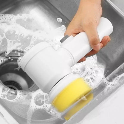 Mão segurando escova elétrica branca com esponja amarela limpando pia de aço inox com espuma